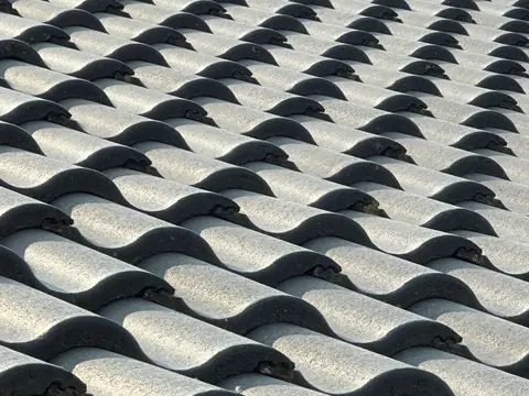 Pale gray concrete S-profile roof tiles in overlapping courses, seen close up