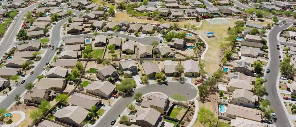 Houses with tan tile roofs around a cul-de-sac in a desert subdivision near Phoenix, seen from the air